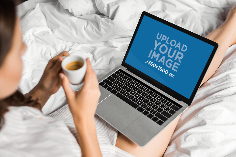 Mockup of a Woman Sitting on Her Bed with a Macbook on Her Legs