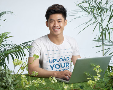 T-Shirt Mockup of a Man Working on His Laptop Featuring Some Plants
