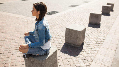Edgy Young Woman Wearing a T-Shirt Stop Motion Sitting on a Cube Outdoors