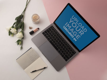 MacBook Template on a White and Pink Surface Near Flowers and a Notebook