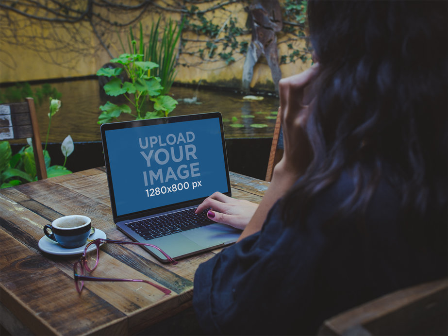 Woman Talking on the Phone Using a MacBook Pro Mockup Near a Fountain