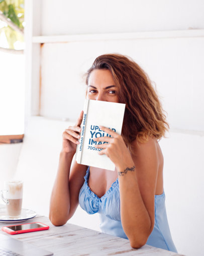 Mockup of a Woman Holding a Book Close to Her Face