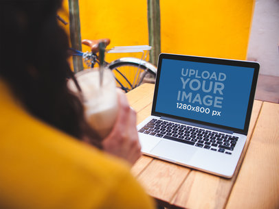 Over Shoulder Mockup of a Woman Using a MacBook on a Wooden Table a19521