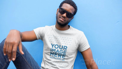 Young Man with Sunglasses Wearing a T-Shirt Video Sitting on the Sidewalk