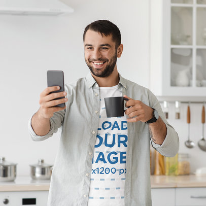 T-Shirt Mockup of a Smiling Man with a Coffee Mug Taking a Selfie in His Kitchen m18230 r-el2