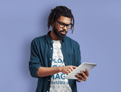 Tee Mockup of a Bearded Man with Glasses Using a Tablet