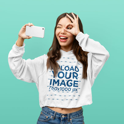 Crop Top Hoodie Mockup Featuring a Woman Taking a Fun Selfie Against a Colorful Background m25785 r-el2