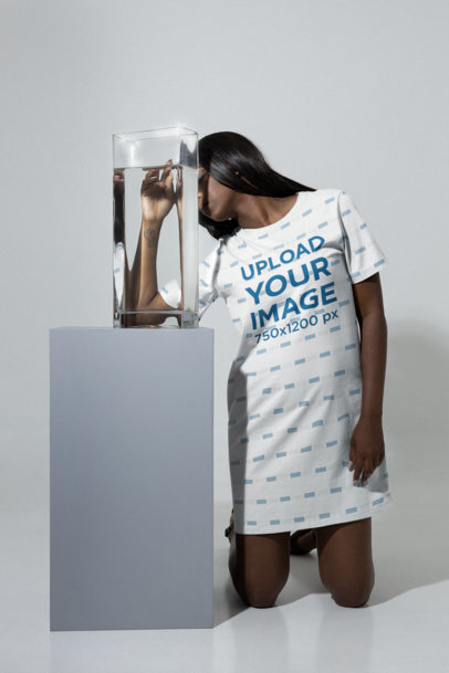 Mockup of a Woman Wearing a T-Shirt Dress With a Vase Next to Her