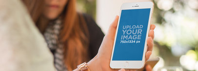 Mockup of a Woman Holding an iPhone 6 in Portrait Position Beside Her Friend