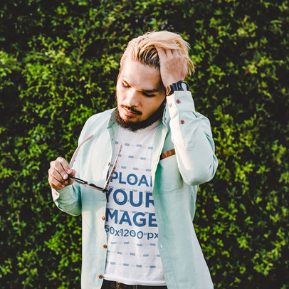 Heathered T-Shirt Mockup of a Man With Dyed Hair Posing Against a Grass Wall