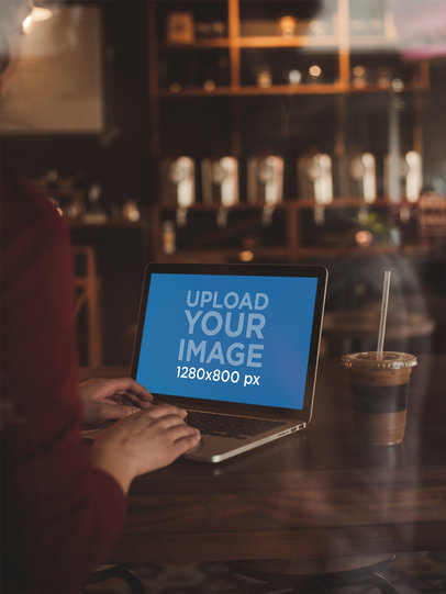 Through the Window Mockup of a MacBook Pro Being Used at a Cafe