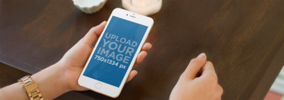 Woman Looking at an iPhone 6 in Portrait Position at a Table Mockup