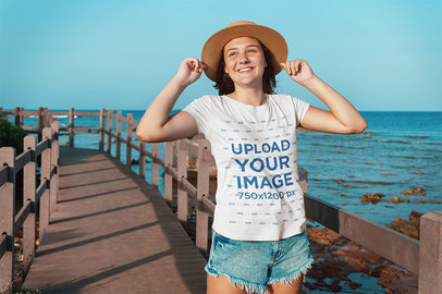 T-Shirt Mockup Featuring a Smiling Girl on a Bridge by the Beach