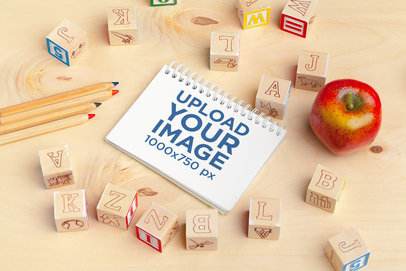 Mockup of a Notebook Placed Next to Some Blocks and Pencils
