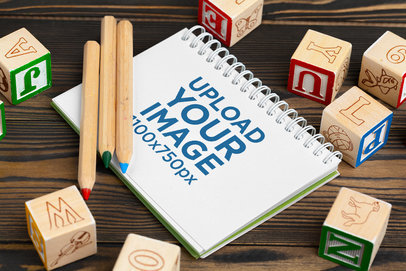 Mockup of a Notebook Surrounded by Alphabet Blocks and Colored Pencils