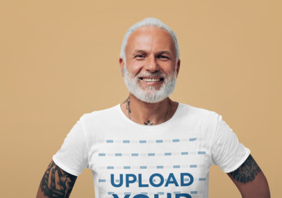 T-Shirt Mockup Featuring a Happy Tattooed Senior Man at a Studio With a Customizable Background