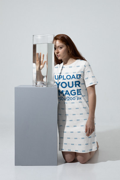 Mockup of a Woman Wearing a T-Shirt Dress Next to a Glass Vase