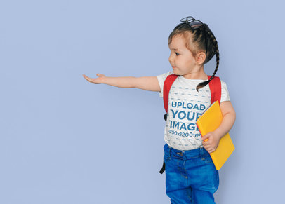 Round-Neck Tee Mockup of a Little Girl with a Backpack Holding a Book