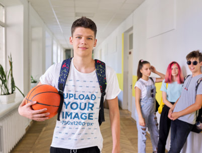 Heathered T-Shirt Mockup Featuring a Young Male Student Holding a Basketball Ball