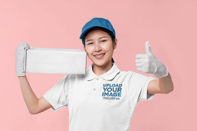 Polo Shirt Mockup Featuring a Cheerful Woman Holding a Box and Giving Thumbs-Up