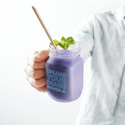 Mason Jar Mockup of a Man Holding a Blueberry Smoothie Close to the Camera