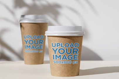 Mockup of Two Paper Cups Against a White Wall