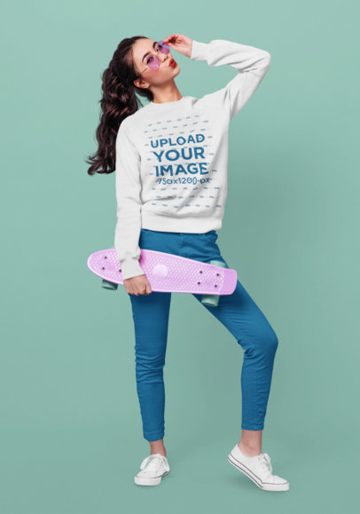 Mockup of a Woman Wearing a Sweatshirt and Posing with a Skateboard at a Studio