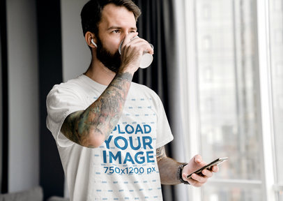 T-Shirt Mockup of a Bearded Man with Arm Tattoos Drinking Coffee