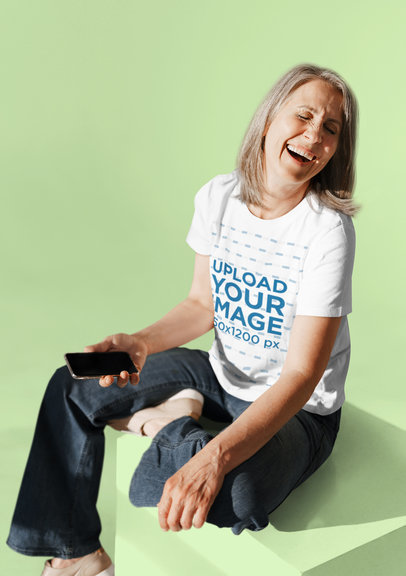 T-Shirt Mockup of a Cheerful Senior Woman Laughing While Using a Phone