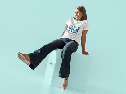 T-Shirt Mockup Featuring a Happy Senior Woman Sitting o a Cube