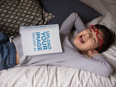 Hispanic Kid Laughing with a Book Mockup on Bed