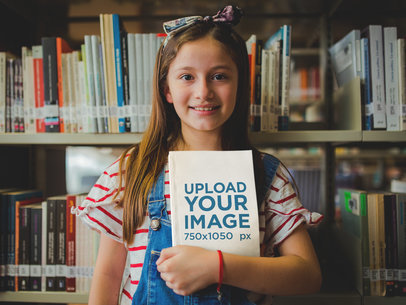 Happy Little Girl Holding a Book Mockup at the Library a19273