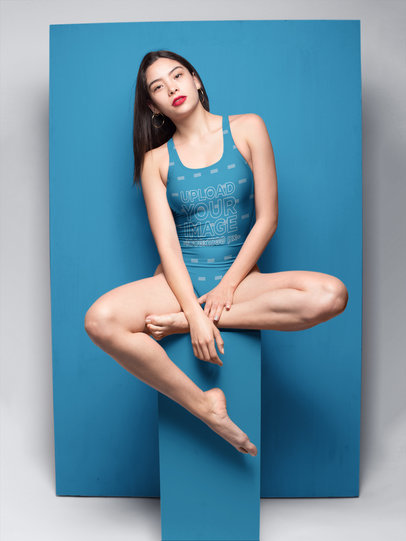 Woman Wearing a Swimsuit Mockup Sitting on a Stool Against a Big Paper