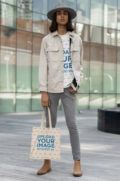 Mockup of a Tote Bag Featuring a Man Wearing a T-Shirt and a Hat