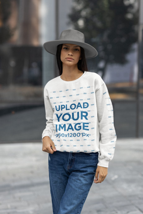 Mockup of a Woman Posing on a Street with a Sweatshirt and a Hat
