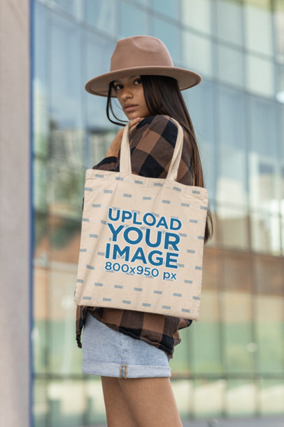 Mockup of Serious Woman With a Brown Hat Holding a Tote Bag