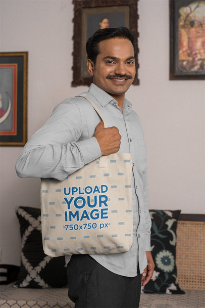 Mockup of a Man With Mustache Holding a Tote Bag at Home