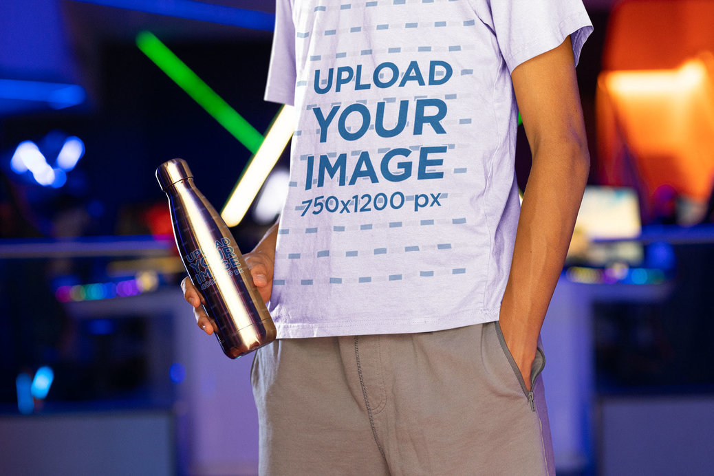 T-Shirt Mockup of a Man Holding an Aluminum Bottle at an Arcade 