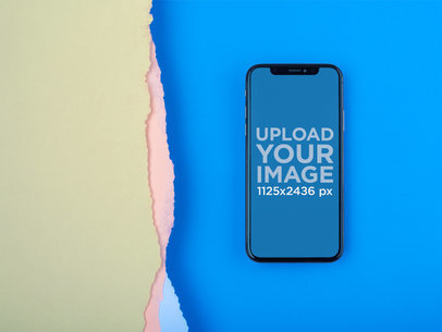 iPhone 11 Pro Mockup Lying on a Blue Surface Near Broken Paper