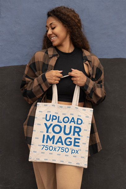 Mockup of a Happy Woman with Curly Hair Holding a Tote Bag