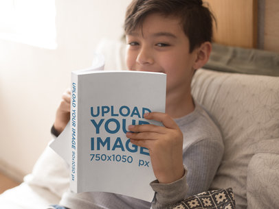 Happy Boy Reading a Paperback Book Mockup on his Couch a19155