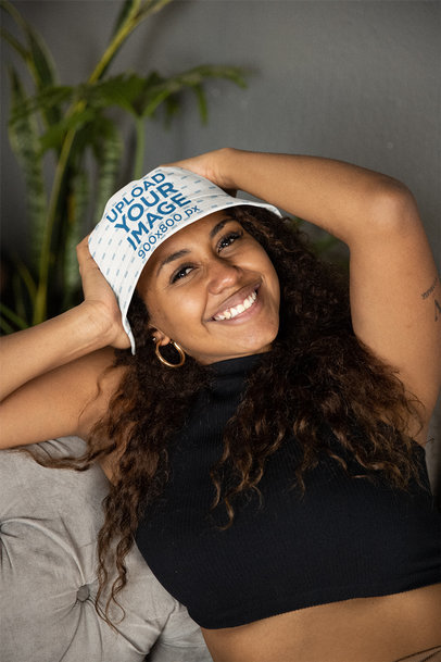 Mockup of a Woman Wearing a Bucket Hat and Chilling on a Sofa