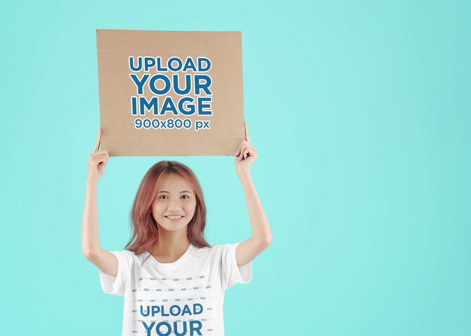 T-Shirt Mockup of a Smiling Woman Holding a Cardboard Sign at a Studio