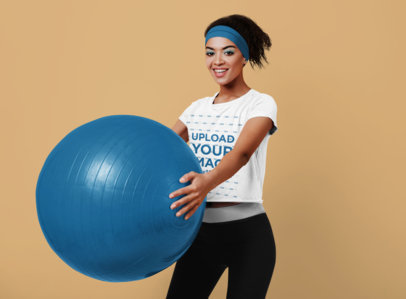 T-Shirt Mockup Featuring a Cheerful Woman Doing Exercise With a Fitness Ball