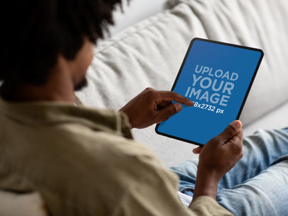 Mockup of a Man Using an iPad While Sitting on a Couch m25742 r-el2
