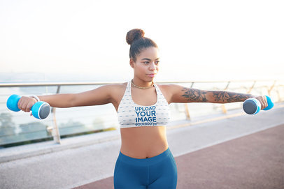 Sublimated Sports Bra Mockup of a Woman Doing an Outdoor Workout with Dumbbells