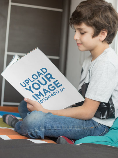Smiling Boy Reading a Paperback Book Mockup on his Bed