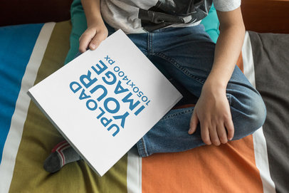 Book Mockup on the Lap of a Boy Sitting on his Bed