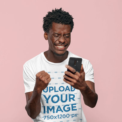 T-Shirt Mockup of an Excited Man With Afro Hairstyle Looking at His Phone