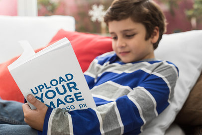 Focused Boy Reading a Book Mockup Lying on Pillows